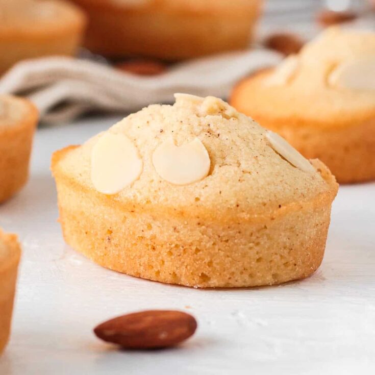 Two brown butter fanciers on a white counter top with whole almonds scattered about.