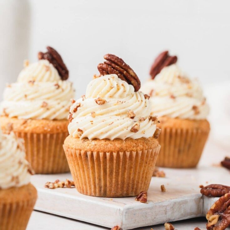 Three brown butter pecan cupcakes on a white stone platter.