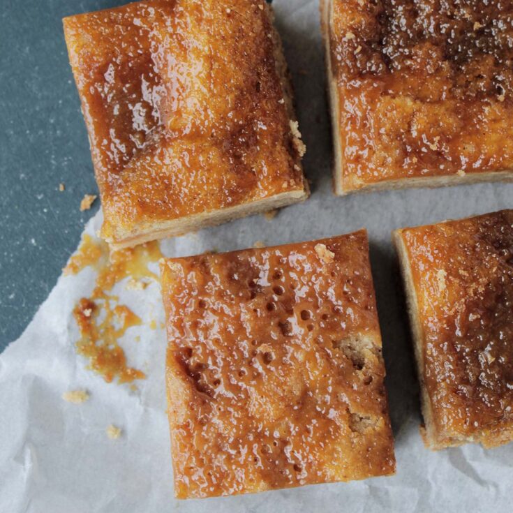 Four caramel blondies cut in to squares on a piece of white parchment paper.