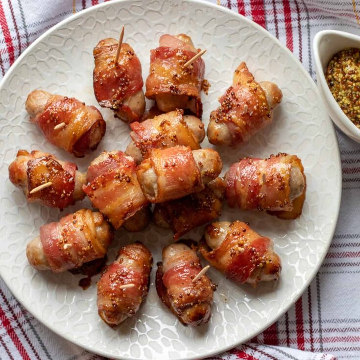 Several pieces of homemade pigs in a blanked on a white serving plate.