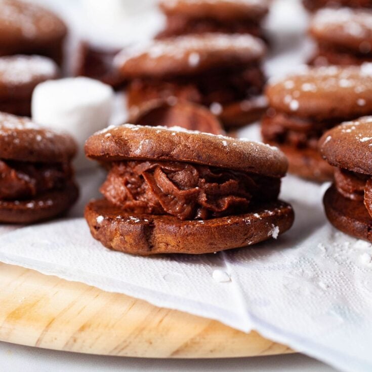 Several chocolate mascarpone cookies on a white napkin on a wooden serving tray.