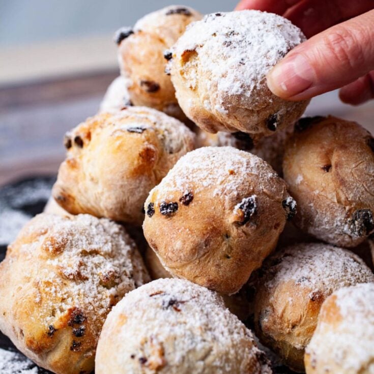 A large mound of zeppole piled on top of each other and dusted with powdered sugar.