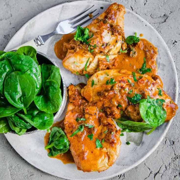 A large plate with creamy sun-dried tomato pesto chicken with spinach.