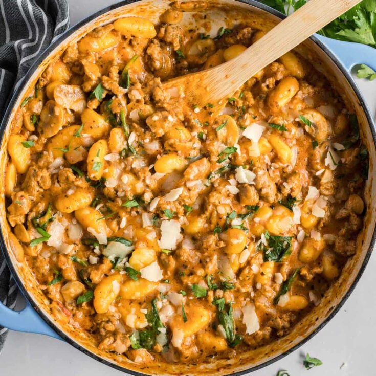 A large pot of creamy potato and sausage gnocchi topped with parmesan cheese.