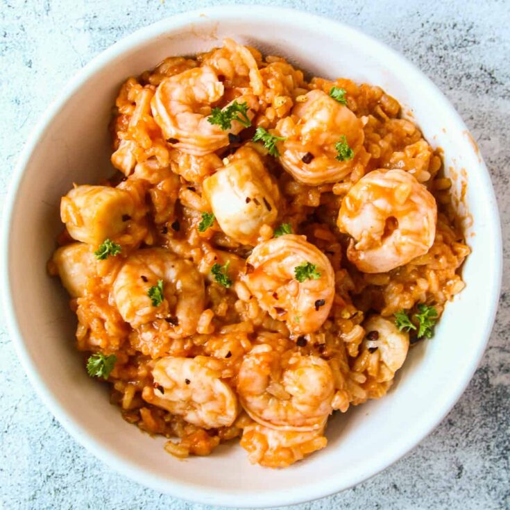 Risotto in a tomato based sauce topped with cooked shrimp.