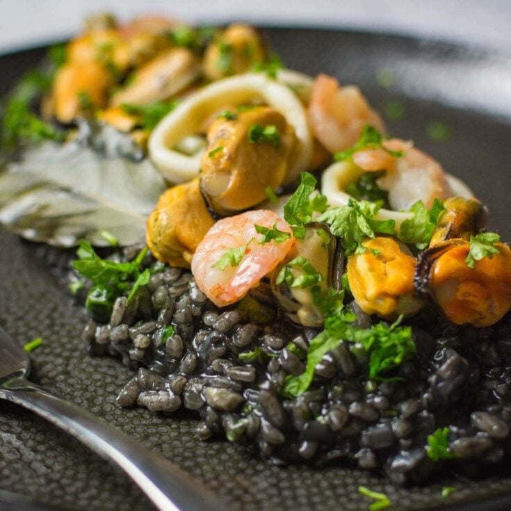 Squid ink risotto topped with cooked shrimp, clams and calamari.